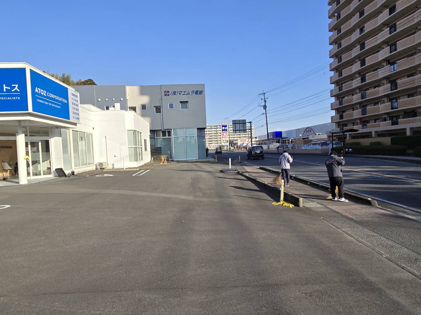 写真：店舗の前の道を掃き掃除する社員たち