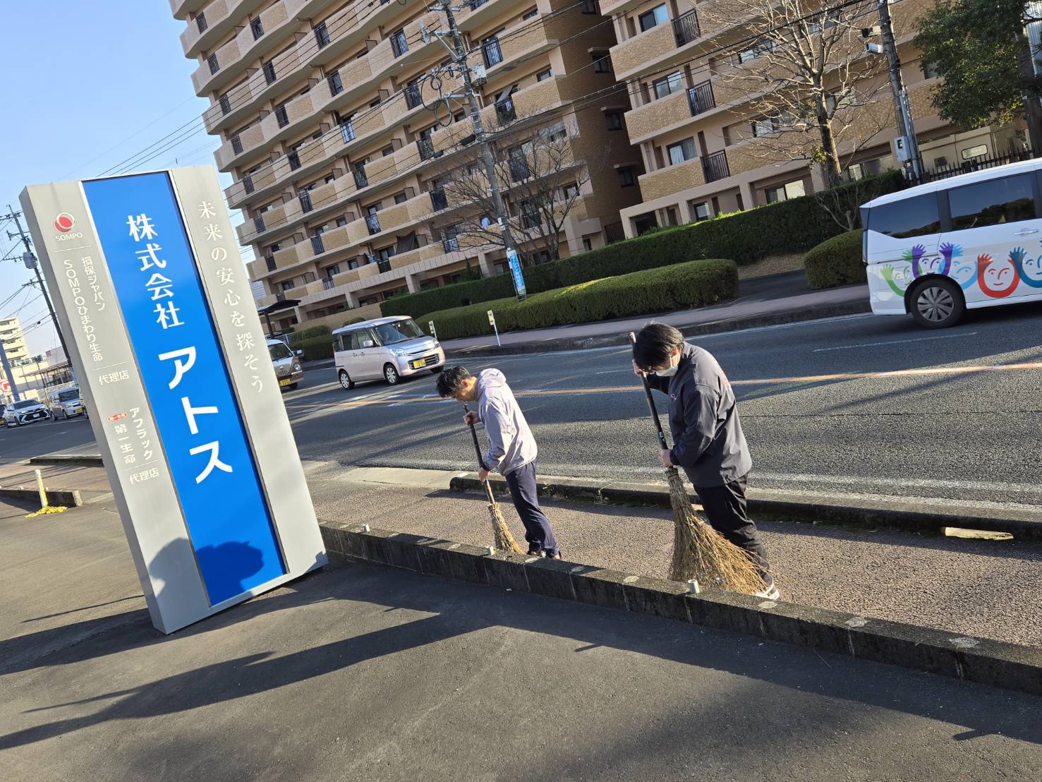 写真：2人の社員が一生懸命掃き掃除をしている様子
