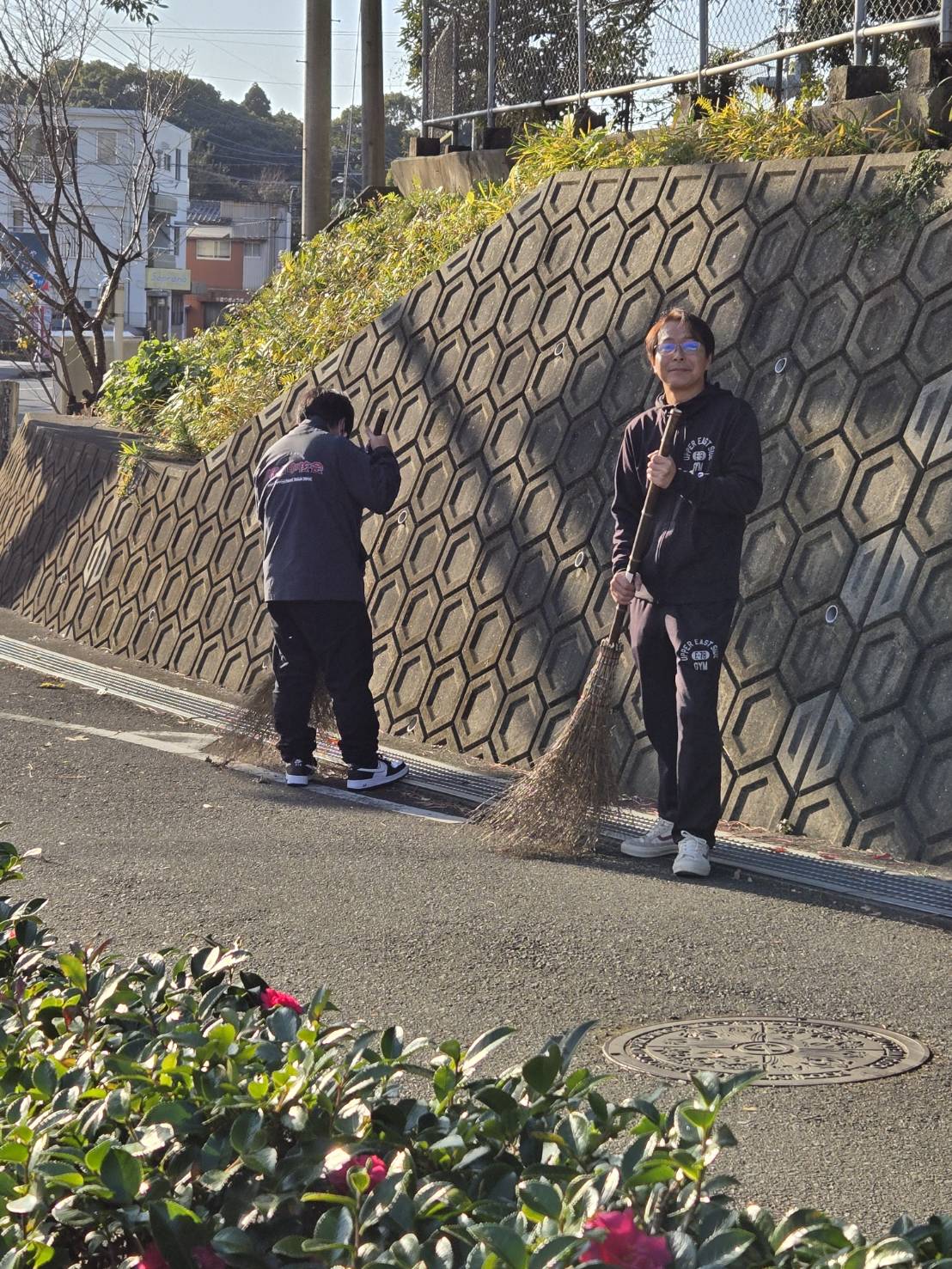 写真：箒を持ってにこやかな笑みを浮かべる社員の様子